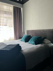 Un dormitorio con una cama con almohadas azules y una ventana en EVIS LTD apartments 1, en Rēzekne