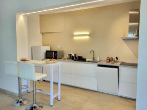 a kitchen with white cabinets and a white table at Un'oasi di pace in riva al mare in Pittulongu