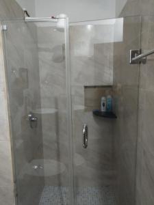 La salle de bains est pourvue d'une douche avec une porte en verre. dans l'établissement Amplia habitacion a 10min del Aeropuerto, à Cancún