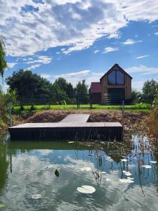 a house in the middle of a pond with a building at Zielona Ostoja - domek z prywatnym pomostem przy Obrzycy in Kolsko