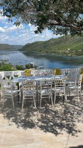 Casa Bela Vista في ببرانا: طاولة بيضاء وكراسي مطلة على البحيرة