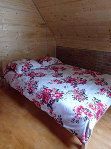 - une chambre dotée d'un lit avec un couvre-lit floral dans l'établissement Koliba Joca, à Lepterija