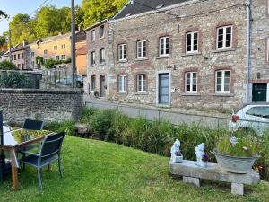 einen Garten mit einem Stuhl und einem Steingebäude in der Unterkunft Charmante petite maison à Olne in Olne