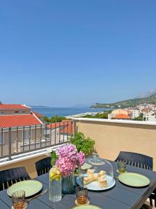 a table with plates of food and flowers on a balcony at Luxury Apartments Luna in Tučepi