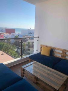 a living room with a blue couch and a large window at Cosy Appartement with sea view in Plage de Mehdia