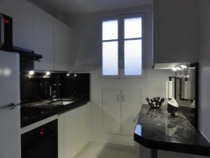 een witte keuken met een wastafel en een raam bij L'Escapade parisienne in Parijs
