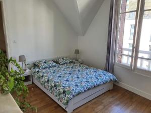 a bedroom with a bed with a blue comforter at 2 chambres dans une maison proche de Paris et du Stade de France in Enghien-les-Bains
