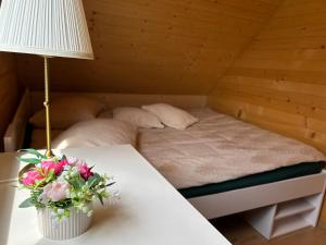 米沃姆溫的住宿－Dom Miłomłyn，一张带桌子的床,上面有台灯和鲜花