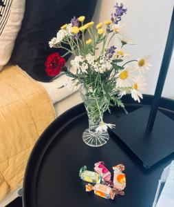 una mesa con un jarrón de flores y dulces en Litet gårdshus en Älandsbro