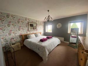 een slaapkamer met een bed met roze bloemenbehang bij Carreg Y Garth Isaf - Hot Tub Nr Zip World in Bangor