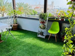 einen Balkon mit grünem Gras und einem grünen Stuhl in der Unterkunft EMAN SWEET HOME - cozy privet unique apartment in haifa downtown in Haifa