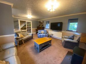 a living room with couches and a tv at Carreg Y Garth Isaf - Hot Tub Nr Zip World in Bangor