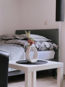a white table with a vase on top of a bed at Cozy Apartment in historical Alt-Lobeda near Uni-Klinik Jena in Jena