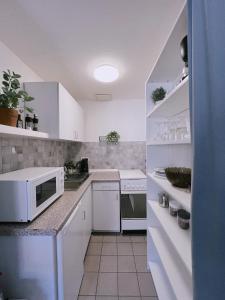 uma cozinha com armários brancos e um micro-ondas branco em Cozy Apartment in historical Alt-Lobeda near Uni-Klinik Jena em Jena