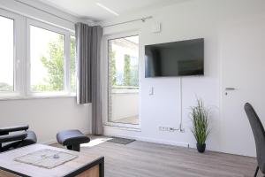 ein weißes Wohnzimmer mit einem Tisch und einem TV in der Unterkunft Weiße Villen Wohnung 19 in Boltenhagen
