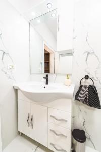 ein Badezimmer mit einem weißen Waschbecken und einem Spiegel in der Unterkunft EVRA APARTMENTS in Recaş