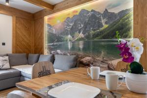 a living room with a table and a painting of a lake at Chata Herkulesa in Zakopane