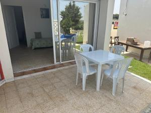 uma mesa branca e cadeiras num pátio em DAR AROUA S3 avec jardin gazonné em El Haouaria