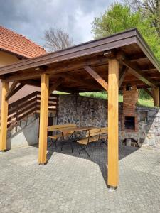 a wooden pavilion with a picnic table and a stone wall at Peaceful, cosy cottage near Kolpa river in Gradac
