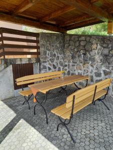 three picnic tables and benches in front of a stone wall at Peaceful, cosy cottage near Kolpa river in Gradac