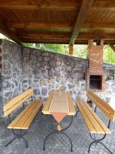 a picnic table with two benches and a stone wall at Peaceful, cosy cottage near Kolpa river in Gradac