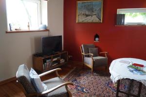 a living room with red walls and a tv and chairs at La Petite Maison in Sart lez Walhain