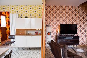 a kitchen with white cabinets and a wall with a geometric wallpaper at Gîte Version 70 in Mondrepuis