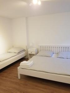 2 Betten in einem Schlafzimmer mit weißen Wänden und Holzböden in der Unterkunft Apartment Sesamstraße in Bremen