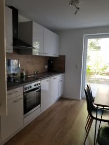 cocina con armarios blancos, mesa y ventana en Apartment Sesamstraße, en Bremen