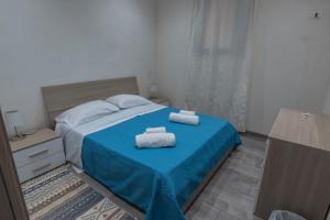 ein Schlafzimmer mit einem blauen Bett und Handtüchern darauf in der Unterkunft Tampasio Apartment Trapani centro in Trapani