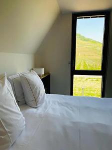 een slaapkamer met een bed met witte lakens en een raam bij Appartements de Manon au cœur des vignes in Kientzheim