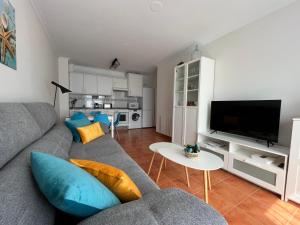 Sala de estar con sofá gris y TV en COSTA MARIÑA Fabuloso apartamento en la costa, en O Vicedo