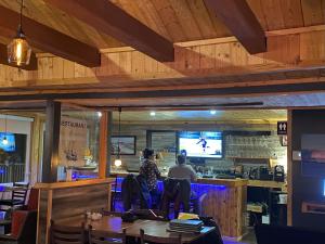 dos personas sentadas en un bar en un restaurante en Hotel-Motel Fleur de Lys en Perce