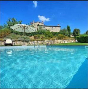 ein großer Pool mit Sonnenschirm und ein Haus in der Unterkunft Chianti Suite in Castellina in Chianti