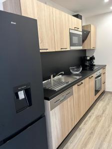 a kitchen with a black refrigerator and a sink at Charmant appartement à Ajaccio in Ajaccio