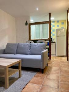 ein Wohnzimmer mit einem blauen Sofa und einer Küche in der Unterkunft Can Julián in L'Escala