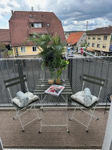 una mesa y 2 sillas sentadas en un balcón en Stilvolles und modernes Appartement mit sonnigem Balkon in Flughafen- und Messenähe 31, en Leinfelden-Echterdingen