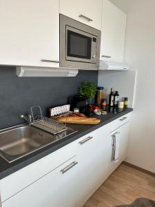 a kitchen with a sink and a microwave at Stilvolles und modernes Appartement mit sonnigem Balkon in Flughafen- und Messenähe 31 in Leinfelden-Echterdingen