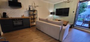 a living room with a couch and a tv at Komfortowy Apartament Przy Bramie Targowej - Old Town in Elblag