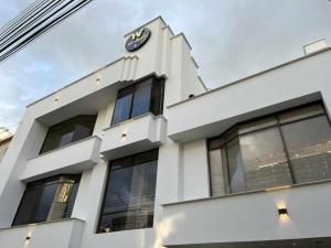 un bâtiment blanc avec une horloge sur son côté dans l'établissement hotel versalles, à Pasto