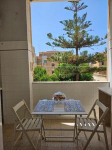 una mesa y sillas en un balcón con un árbol en STAR HOUSE CASA VACANZE, en Marsala