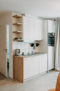 eine Küche mit weißen Schränken und einem Kühlschrank in der Unterkunft Dane river apartment in Klaipėda