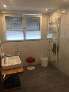 baño con lavabo y taburete rojo en Ferienwohnung „Zur alten Brauerei“, en Mesenich