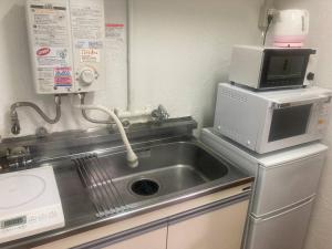 a kitchen with a sink and a microwave at 渋谷駅徒歩6分!高速インターネット光回線 in Tokyo