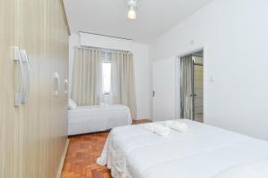 a white bedroom with two beds and a window at Apartamento em ótima localização in Sao Paulo