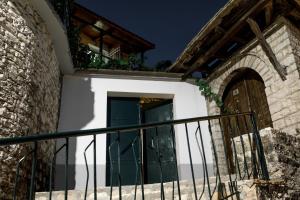 dom z zielonymi drzwiami i kamienną ścianą w obiekcie Martin Villa Gjirokaster w Gjirokastrze