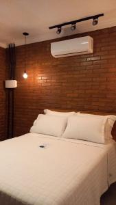 a bedroom with a white bed with a brick wall at Pousada Bem Viver in Nobres