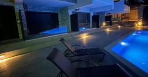 a pool with chairs and a swimming pool at night at Amelia Luxury Suite in Nikiana