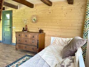a bedroom with a wooden wall with a bed and a dresser at Country House in Vadu Crişului