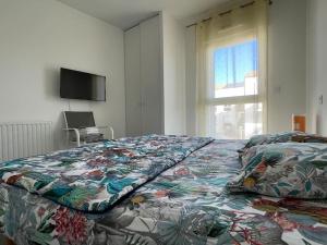 a bed with a colorful comforter in a room with a window at Super appartement, la Guérinière à Noirmoutier in La Guérinière
